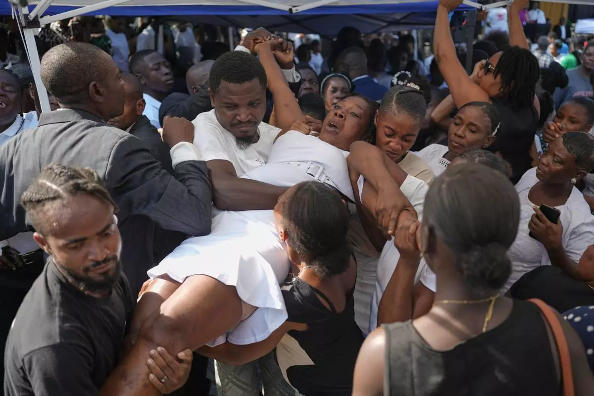 A grieving relatives is carried away during the funeral of people killed by a landslide triggered by Hurricane Melissa in Petit Goave, Haiti, Saturday, Nov. 15, 2025. (AP Photo/Odelyn Joseph)