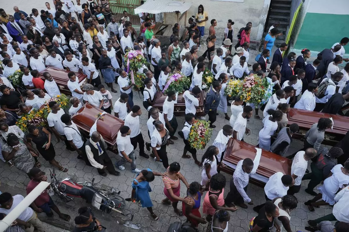 Mourners carry to the cemetery the coffins during the funeral of people killed by a landslide triggered by Hurricane Melissa in Petit Goave, Haiti, Saturday, Nov. 15, 2025. (AP Photo/Odelyn Joseph).