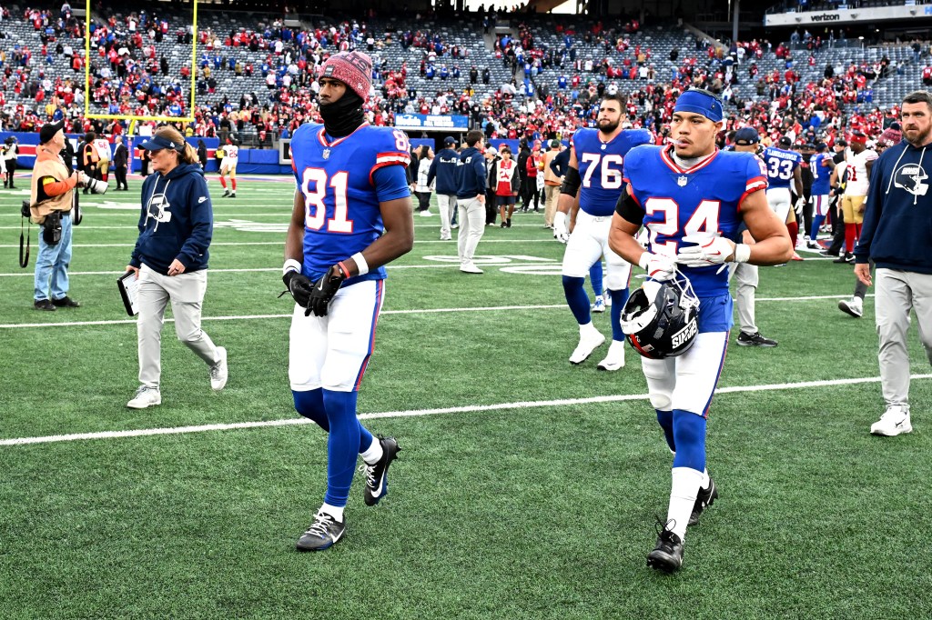 Giants players Beaux Collins (81), Jon Runyan (76), and Dane Belton (24) leave the field after losing a game.