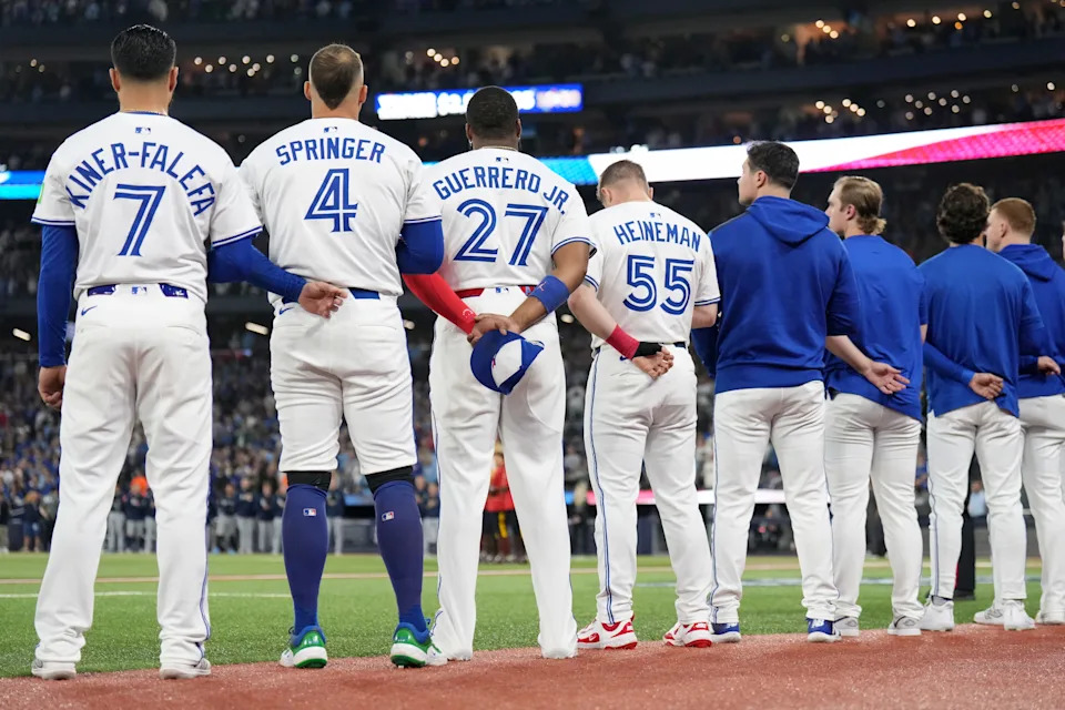 Toronto Blue Jays' Isiah Kiner-Falefa (7), George Springer (4), Vladimir Guerrero Jr. (27), Tyler Heineman (55) and members of the bullpen line up for the singing of the national anthems ahead of first inning MLB American League Championship Series game 7 baseball action against the Seattle Mariners in Toronto, Monday, Oct. 20, 2025. THE CANADIAN PRESS/Nathan Denette
