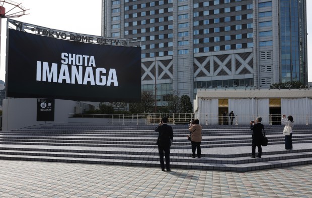 A group of people record a video screen showcasing Japanese...