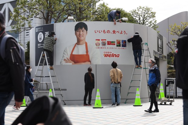 Workers post an outdoor advertisement showcasing Dodgers two-way player Shohei...