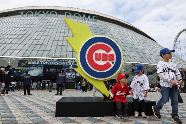 Children sit and stand near a Cubs logo outside the...