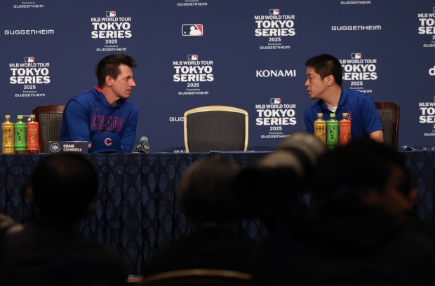 Cubs manager Craig Counsell, left, hears a question through a...
