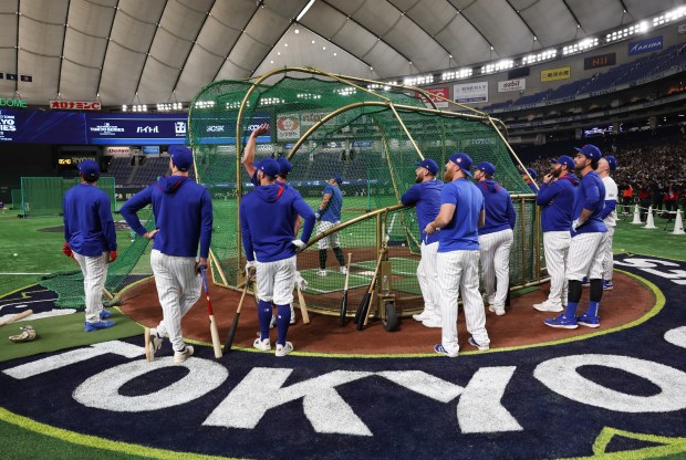 Cubs players watch as outfielder Seiya Suzuki, center, takes batting...