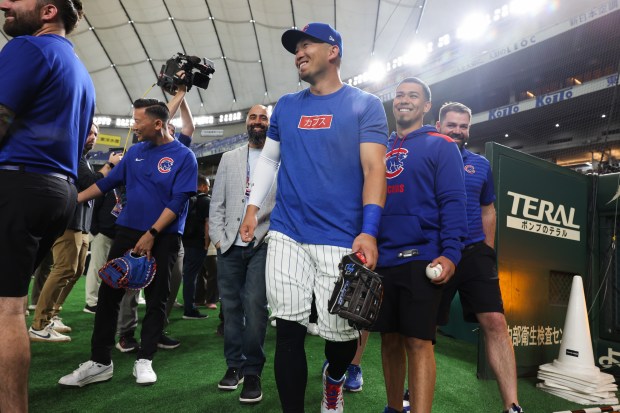 Cubs outfielder Seiya Suzuki, center, walks back to the field...
