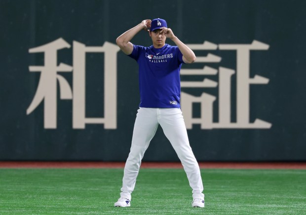 Dodgers two-way player Shohei Ohtani adjusts his cap while working...