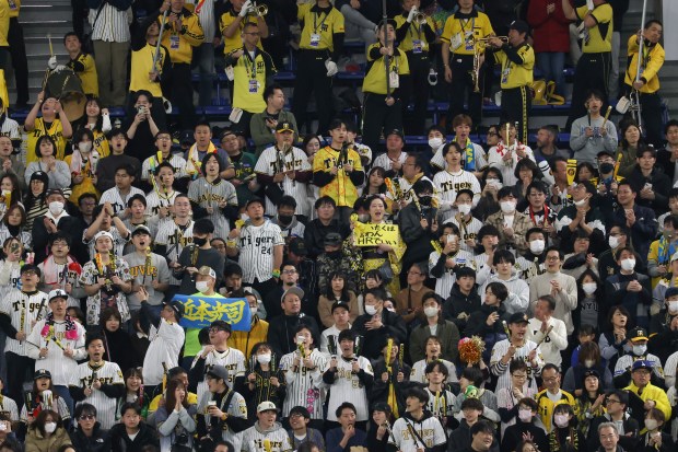 Baseball fans cheer for the Hanshin Tigers in the first...