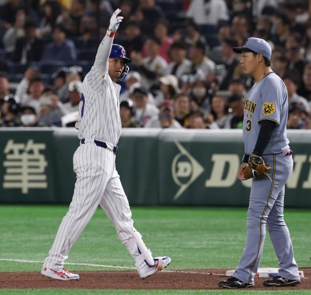 Cubs designated hitter Seiya Suzuki gestures to teammates after hitting...