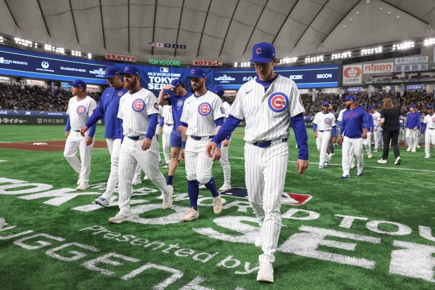 Manager Craig Counsell, right, and Cubs coaches walk off the...