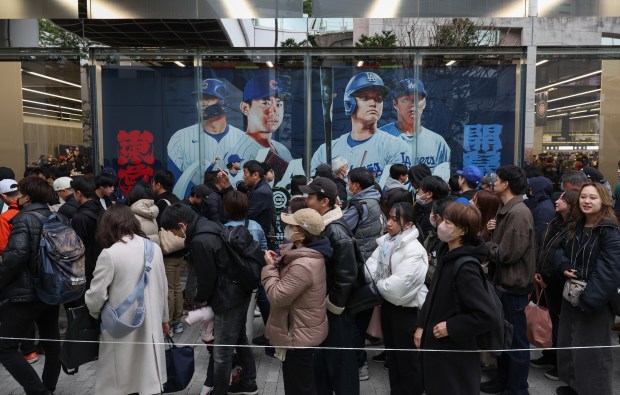 Fans wait to enter an MLB apparel store for the...
