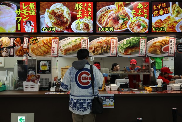 Cubs fan Taisei Notake, 17, picks up his ballpark meal order from a concessions booth before an exhibition game between the Cubs and Yomiuri Giants at the Tokyo Dome on March 16, 2025, in Tokyo. (John J. Kim/Chicago Tribune)