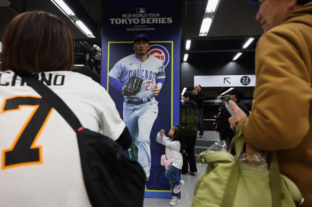 A child makes a batting stance pose next to a...