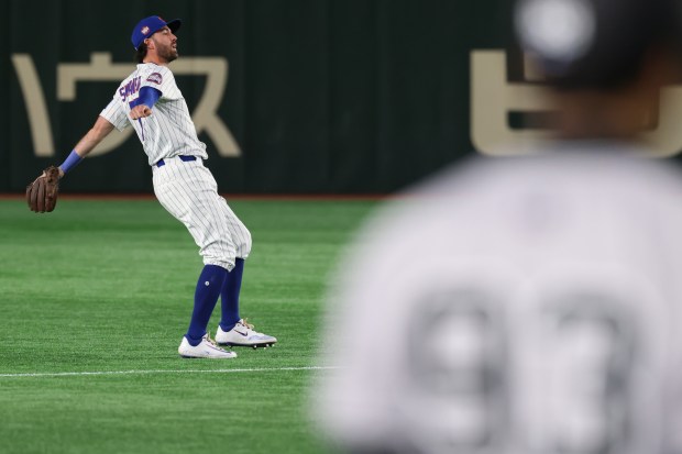 Chicago Cubs shortstop Dansby Swanson follows through on a throw...
