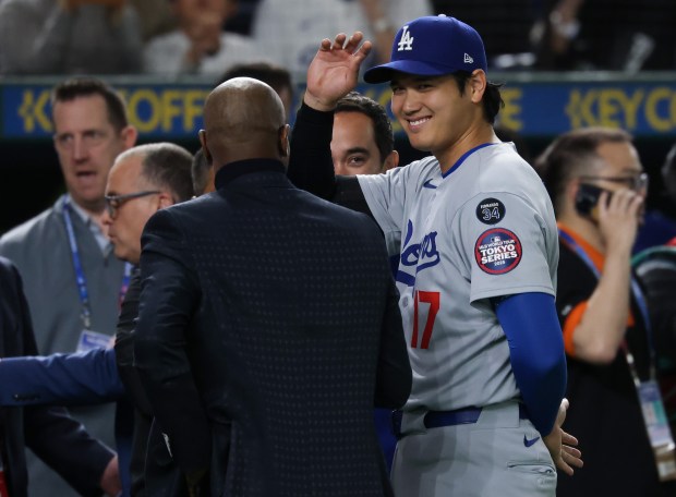Dodgers designated hitter Shohei Ohtani smiles while being congratulated after...