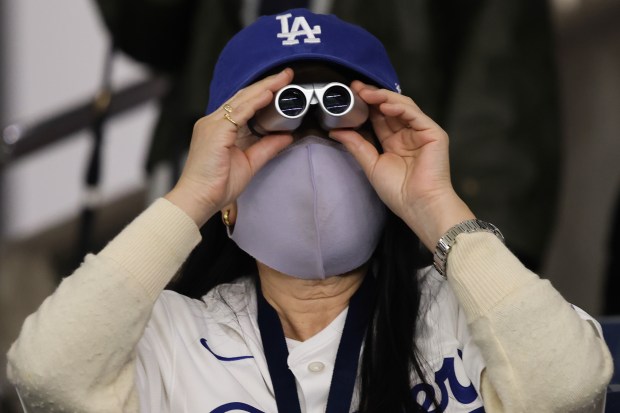 A fan uses binoculars to watch batting practice for the...
