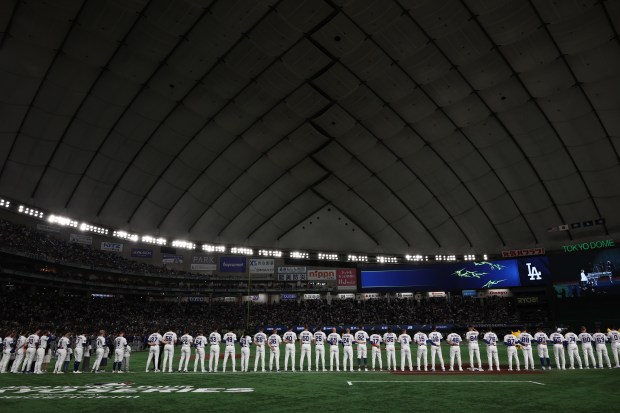 Cubs players and coaches stand for the American and Japanese...