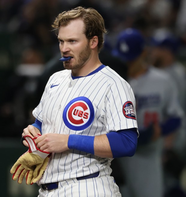 Cubs left fielder Ian Happ takes off his batting gloves...