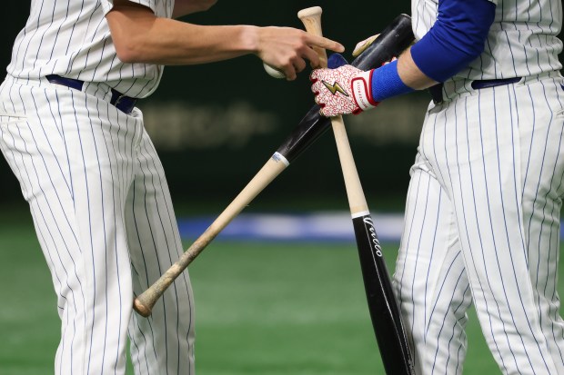 Cubs left fielder Ian Happ, right, switches out a broken...