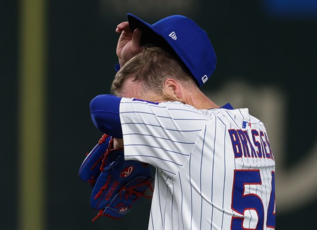 Cubs pitcher Ryan Brasier wipes off sweat in the ninth...