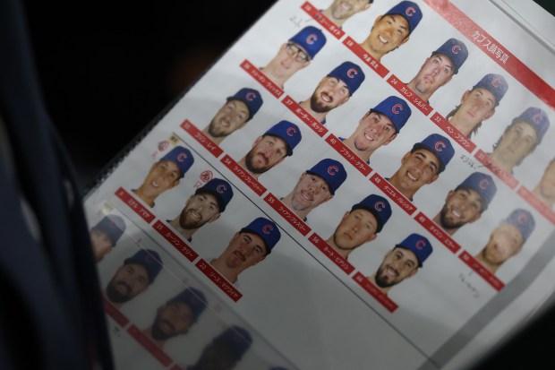 A broadcast producer holds a lineup sheet of Cubs players'...