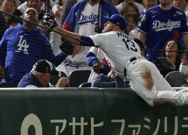 Dodgers third baseman Max Muncy (13) dives into the stands...