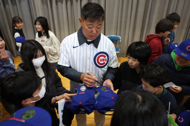 Former Cubs player Kosuke Fukudome signs autographs for students during...