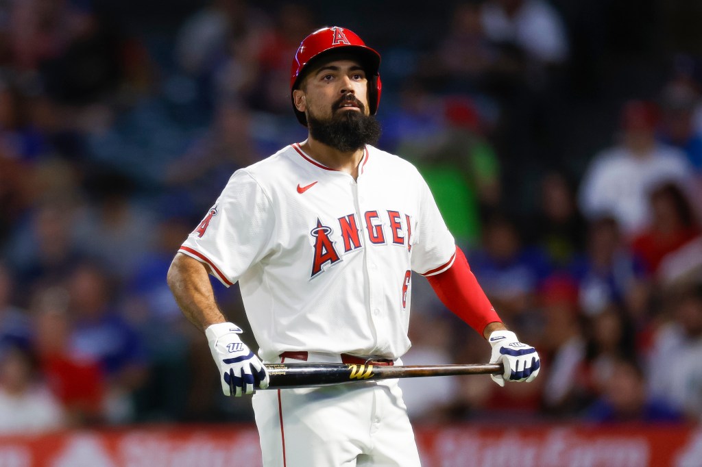 A Los Angeles Angels batter, wearing a red helmet and white uniform, holds a bat.