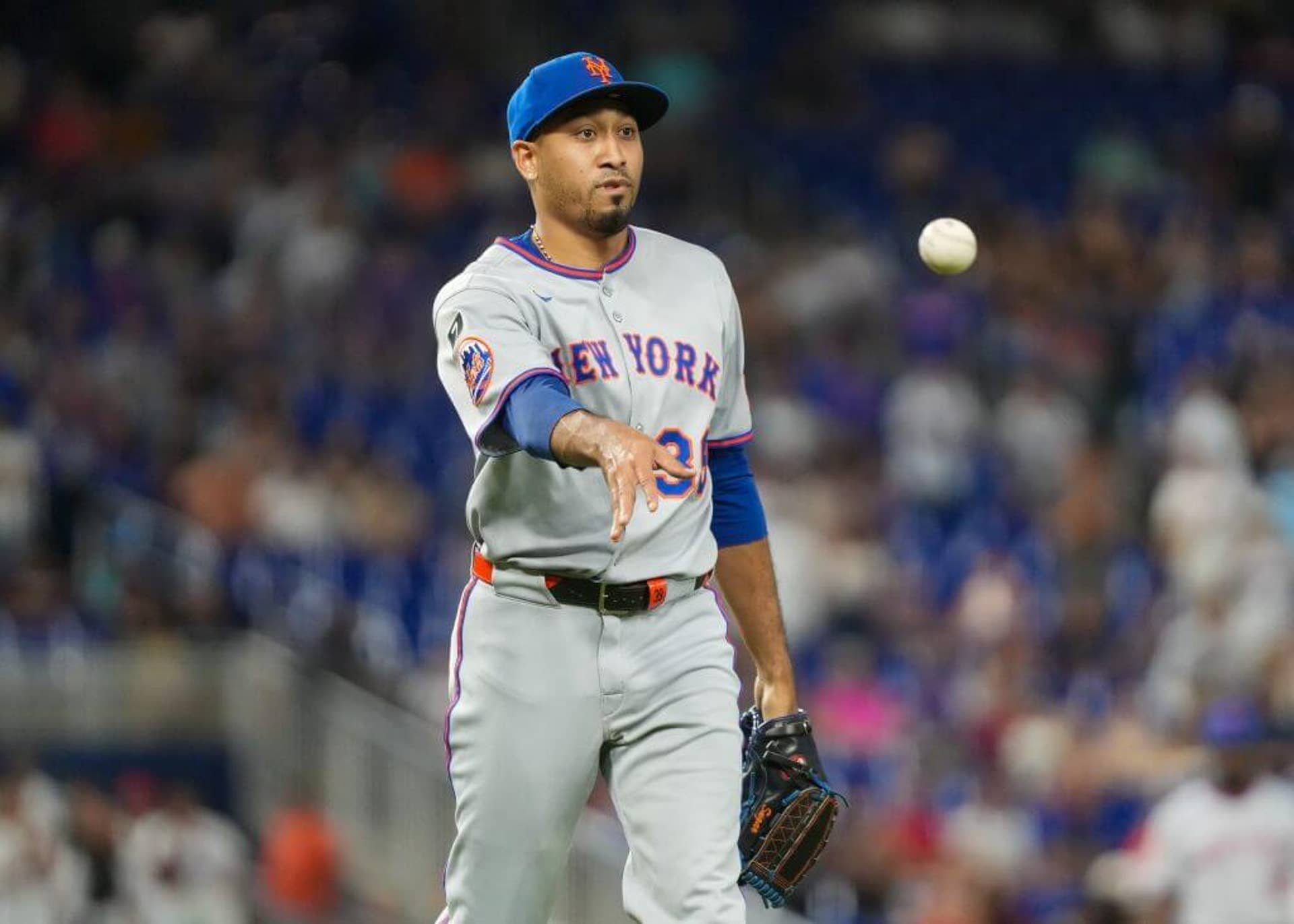 Mets pitcher Edwin Díaz tosses the ball to first base during an MLB game against the Marlins.