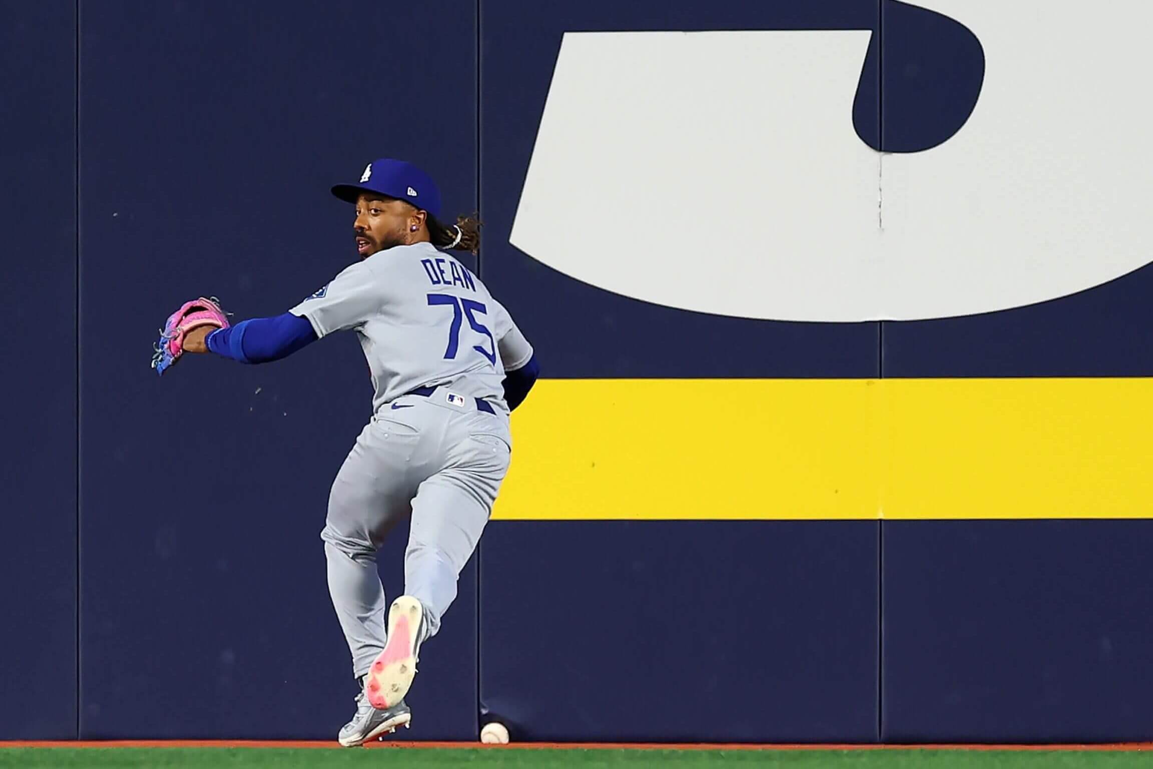 Justin Dean, running toward the outfield wall while looking back toward the infield, alerted umpires that a batted ball was stuck in padding at the base of the wall in Game 6 of the World Series.