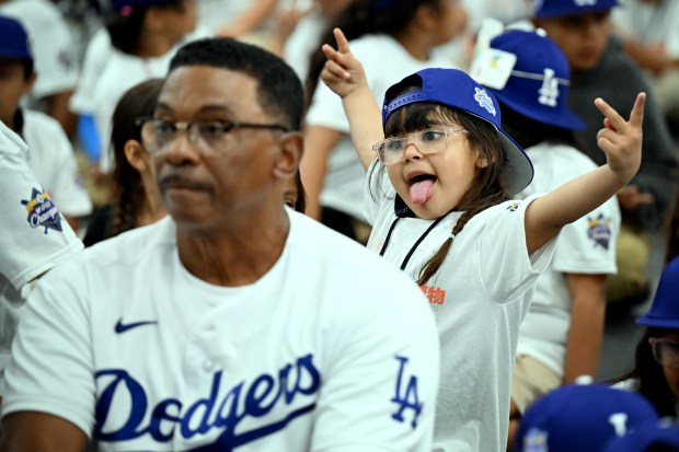 First grader Cataleya Ramirez poses for the cameras behind former...