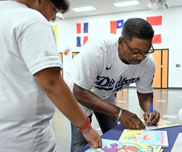 Former Los Angeles Dodgers player Dennis Powell autographs a book...