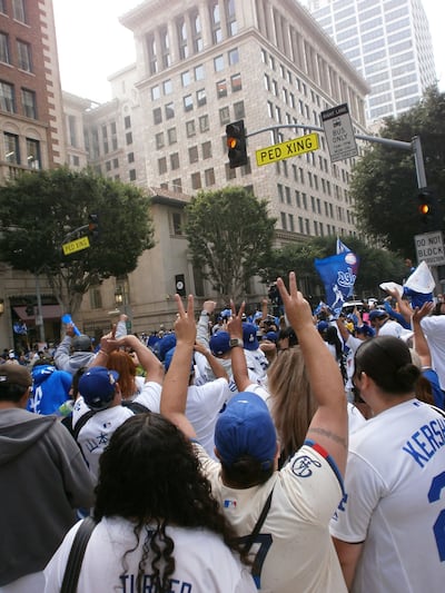 Fans crowd the street in white and blue Dodgers jerseys.