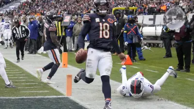 Nov 9, 2025; Chicago, Illinois, USA; Chicago Bears quarterback Caleb Williams (18) scores the game-winning touchdown against New York Giants linebacker Brian Burns (0) during the fourth quarter at Soldier Field.