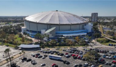 Aerial image of Tropicana Field under bright blue skies with St. Petersburg neighborhoods in the background.