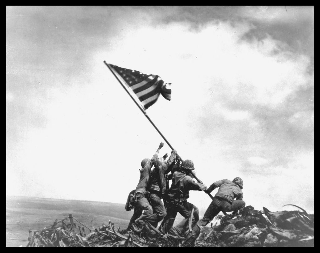 View of members of the United States Marine Corps 5th Division as they raise an American flag on Mount Suribachi during the Battle of Iwo Jima