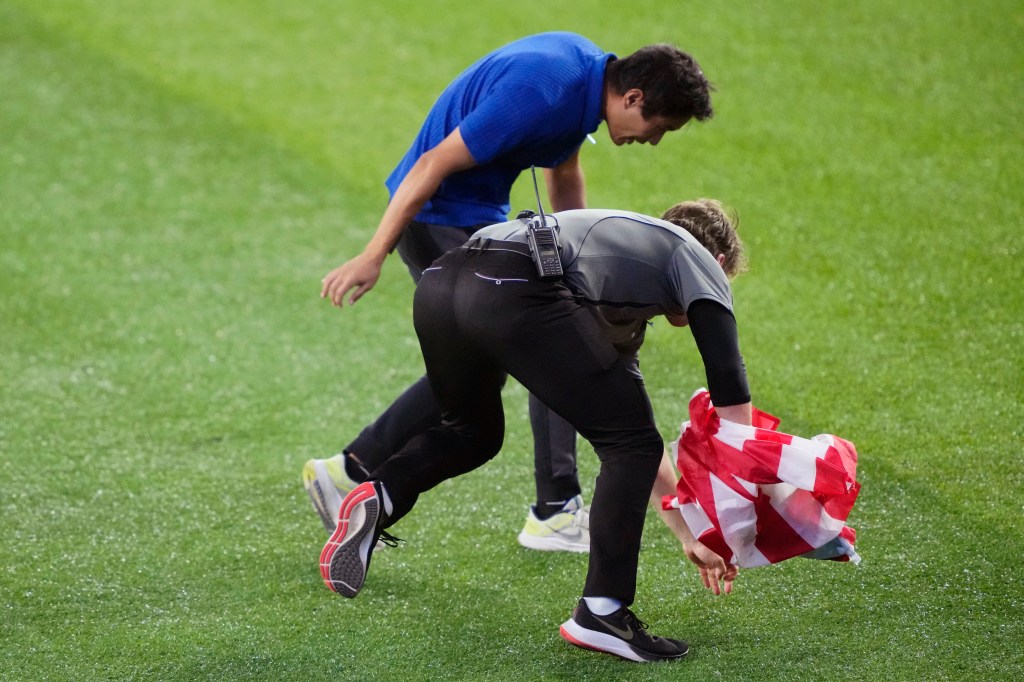Security chasing a fan with a Canadian flag on the field.