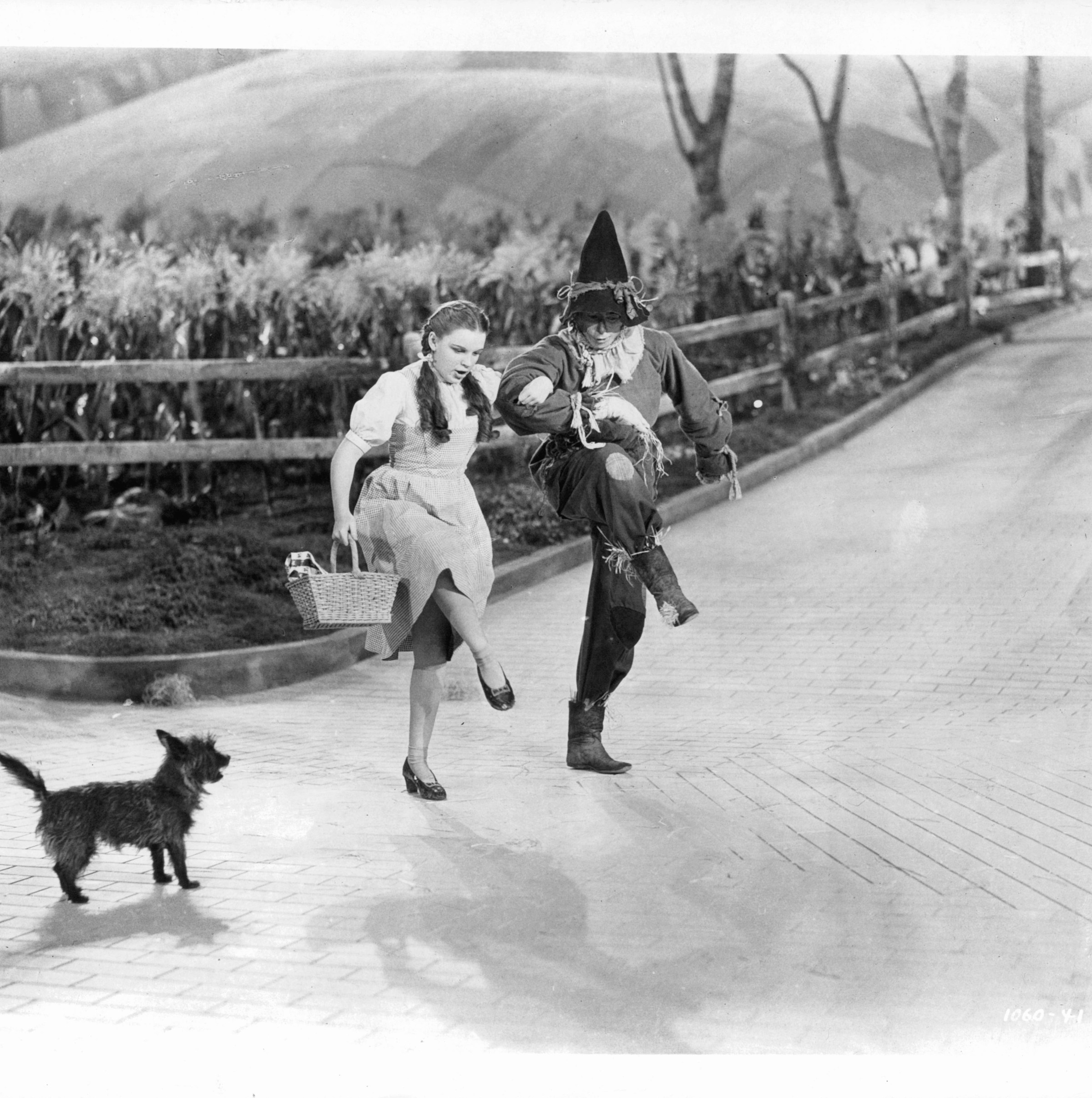 Imagine what that dog is thinking!Actors Judy Garland and Ray Bolger dance in character on the ‘Yellow Brick Road’ as dog dog ‘Toto’ watches, in a scene from the film ‘The Wizard Of Oz’, 1939. (Photo by Metro-Goldwyn-Mayer/Getty Images)