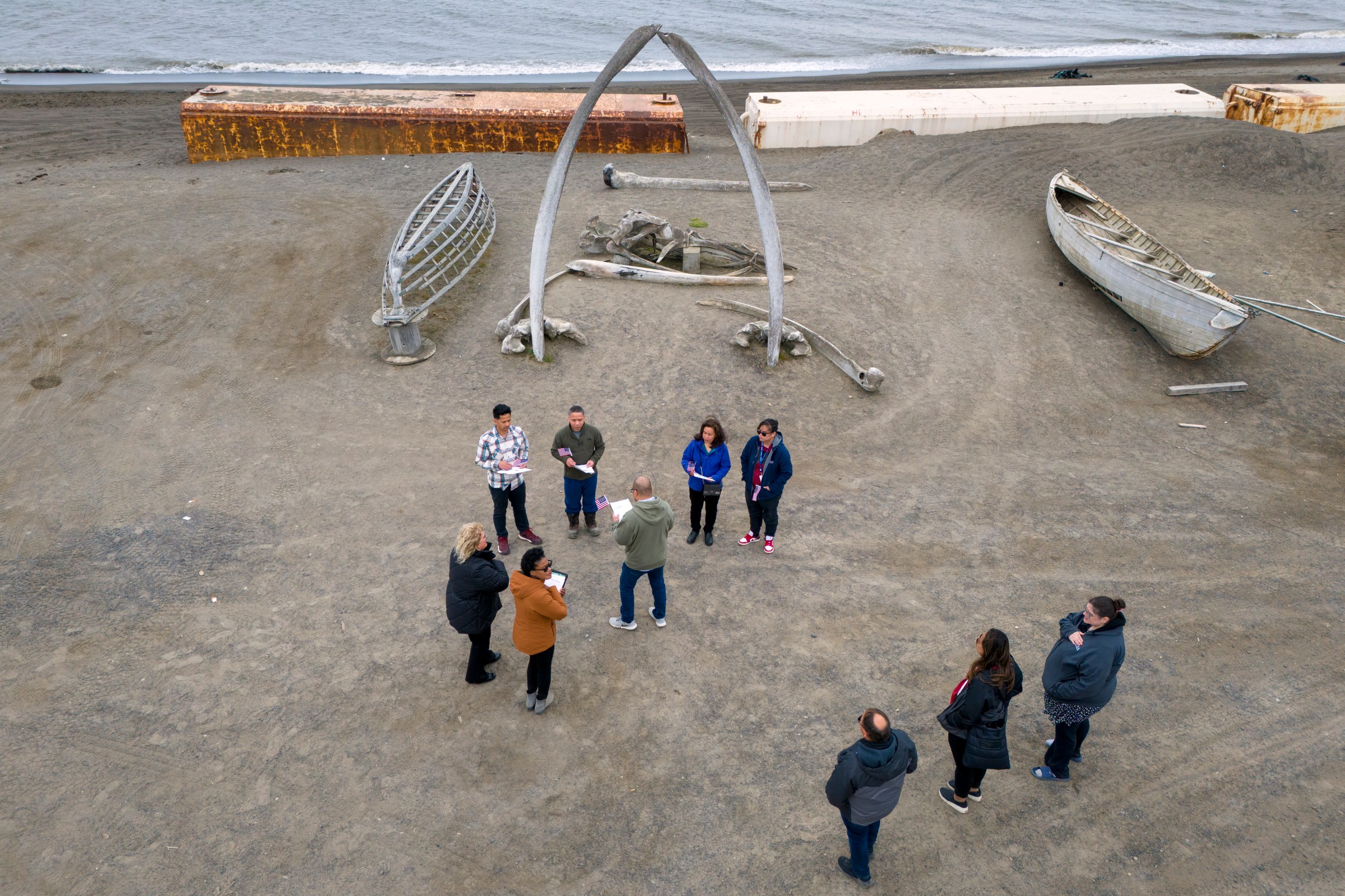UTQIAGVIK, ALASKA - AUGUST 10: Seen from an aerial view, immigrants take part in a naturalization ceremony held in front of the “Gateway to the Arctic” whale bone sculpture on August 10, 2023 in Utqiagvik, Alaska. Located along the Arctic Ocean, Utqiagvik is the northernmost settlement in the United States. Formerly known as Barrow, the town of nearly 5,000 people is mostly populated by indigenous Iñupiat, but also with a growing immigrant population. This year U.S. Citizenship and Immigration Services (USCIS), who held the ceremony, launched a nationwide effort to bring immigration services to remote locations to help legal immigrants, often green card holders, to become American citizens. In the case of Utqiagvik, petitioners would have normally needed to take the two-hour flight to Anchorage, often multiple times, for citizenship appointments. The USCIS effort puts into effect the Biden Administration’s Executive Order 14012, Restoring Faith in Our Legal Immigration Systems and Strengthening Integration and Inclusion Efforts for New Americans. The order, issued on February 2, 2021, instructs U.S. government agencies to promote citizenship through naturalization, improve the naturalization process overall and reduce wait times for applicants. It also revoked a Trump-era memorandum designed to slow and ultimately restrict legal immigration. (Photo by John Moore/Getty Images)