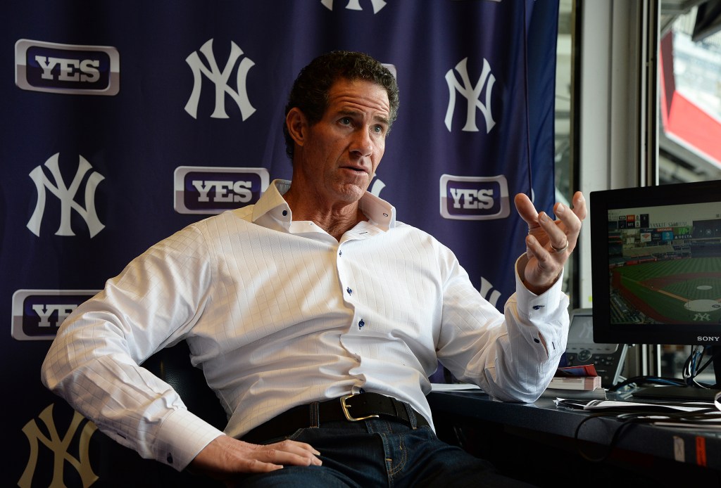 Paul O'Neill speaking with a monitor showing a baseball game and New York Yankees and YES Network logos in the background.