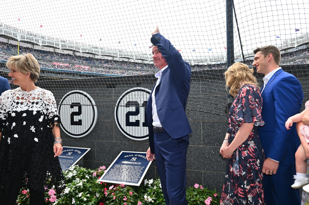 Paul O'Neill waves to fans while standing near his retired number "21" and Derek Jeter's retired number "2" in Monument Park.