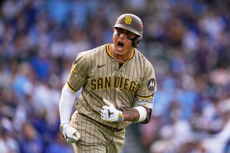 A baseball player in a Padres uniform yells as he starts his trot after hitting a home run.