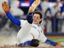 Toronto Blue Jays' Ernie Clement slides into home plate to score on a double by Andrés Giménez during the sixth inning of World Series Game 7.