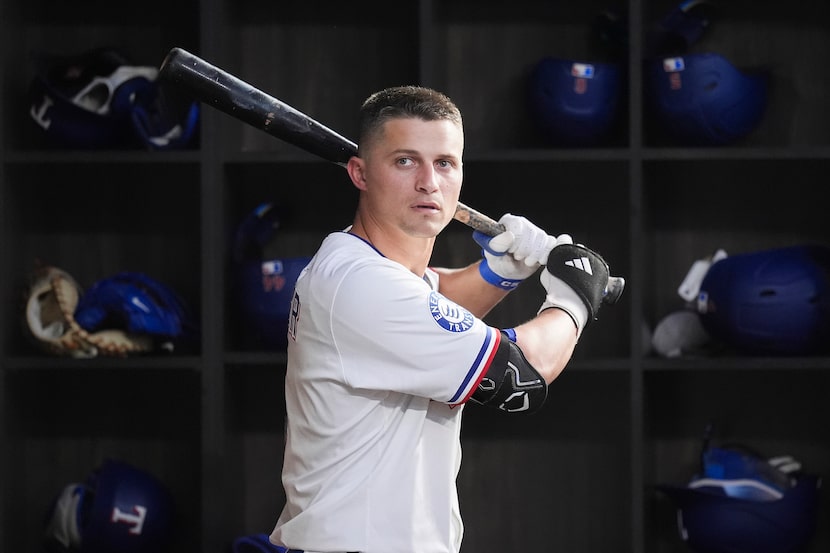 Texas Rangers shortstop Corey Seager picks up a bat in the dugout during the fourth inning...