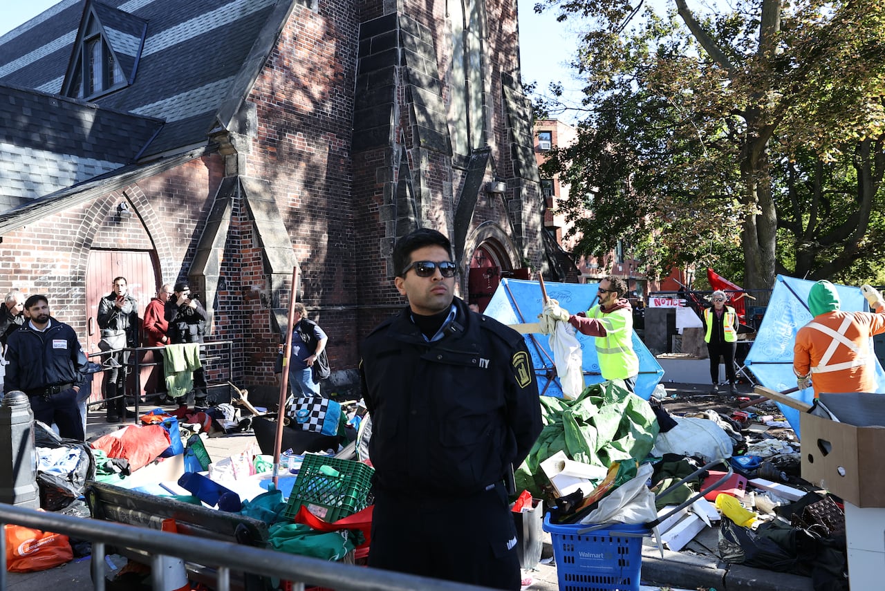 A security guard standing outside a church where an encampment is being cleared.
