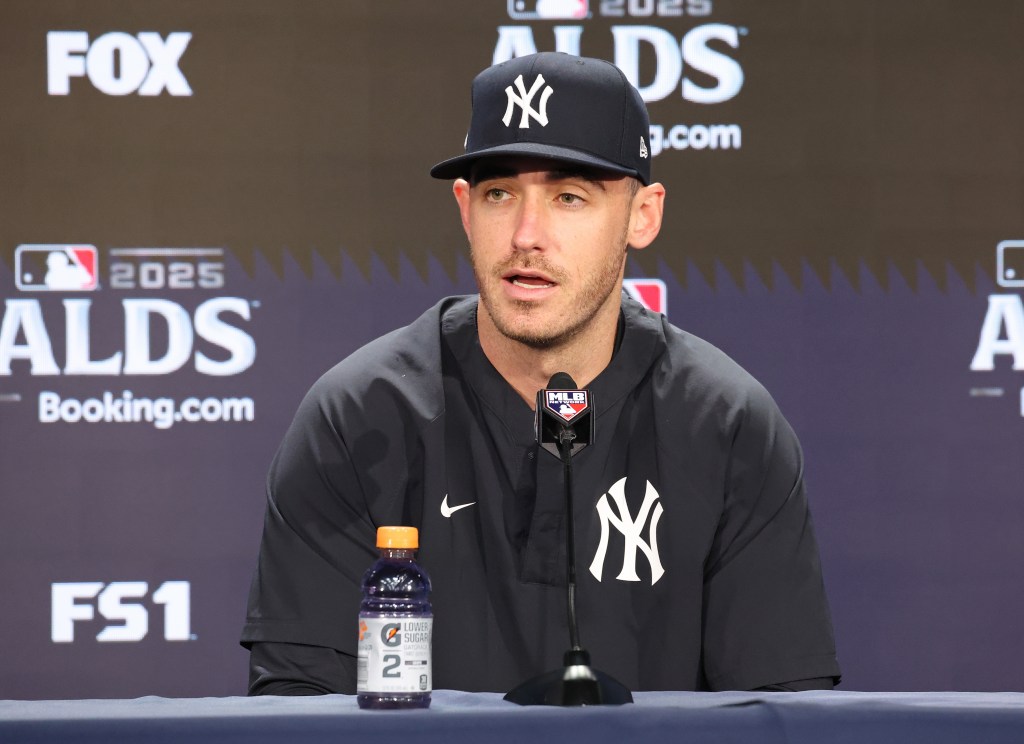 New York Yankees left fielder Cody Bellinger wearing a Yankees cap and jacket while speaking at a press conference.