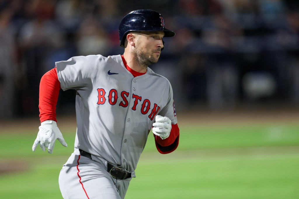 A Boston Red Sox player wearing a helmet and a grey uniform with "BOSTON" written in red on the front, running on a green baseball field.
