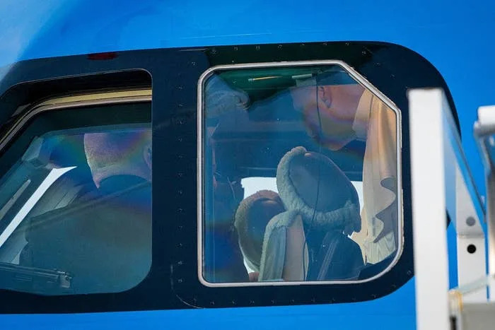 Pilot inside an airplane cockpit, visible through the window, preparing for a flight