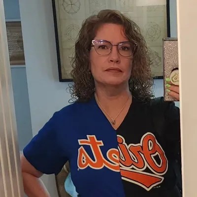 woman with glasses wearing a mets and orioles shirt