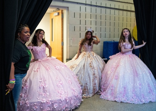 Brittany Jakubowski, a teacher at Catonsville Middle School holds the curtain back for Marley Quintanilla, Nathalie Ramos, and Camila Perez before they head on stage for a fashion show during Diversity Fair, in Catonsville, Wednesday, May 7, 2025.